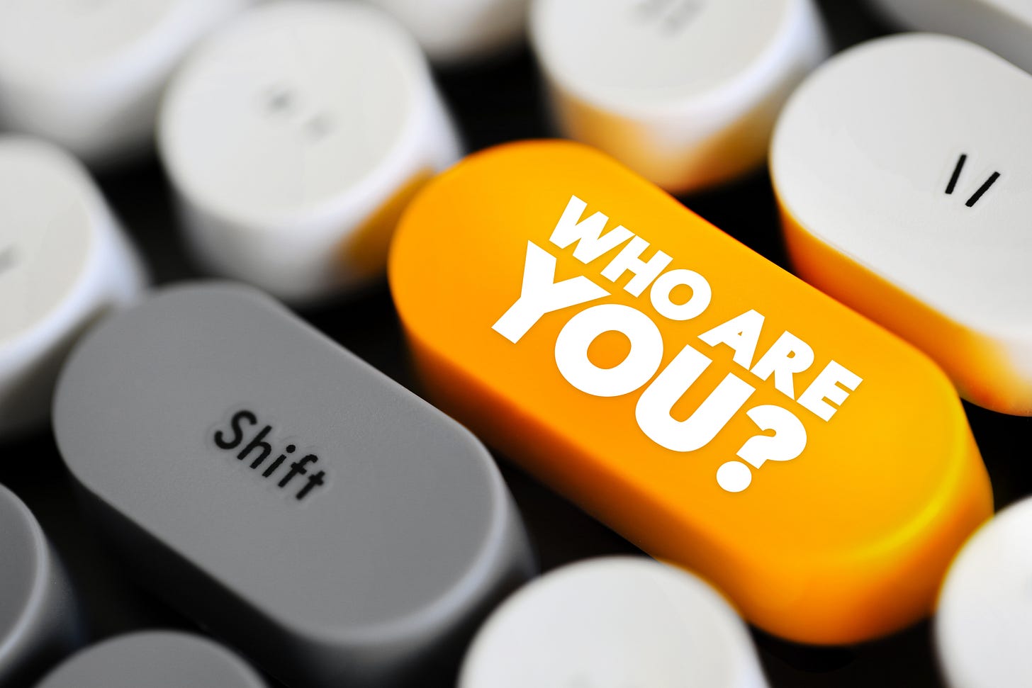 Partial image of a keyboard. The Enter key is in yellow with white text on it asking the question, "Who are you?"