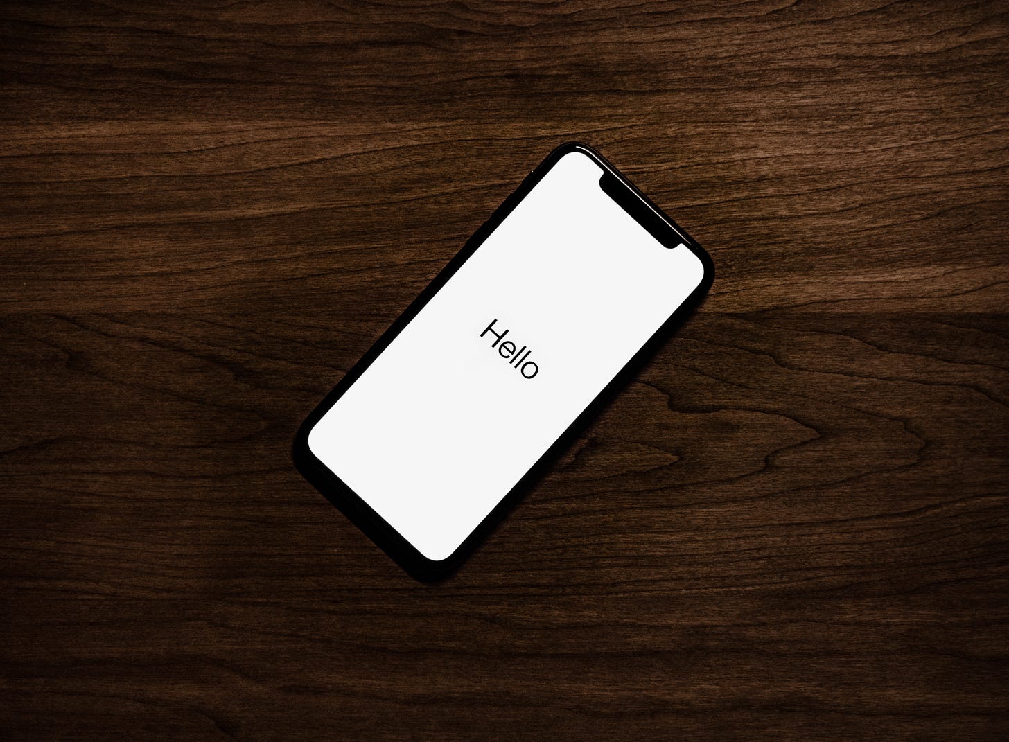 This image shows an iPhone with text saying "Hello" displayed on the phone