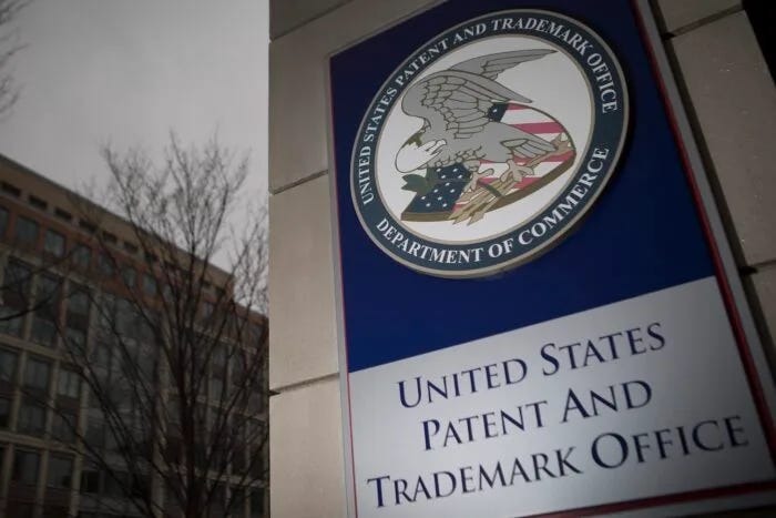 Sign outside the United States Patent and Trademark Office building featuring the USPTO seal and Department of Commerce branding.