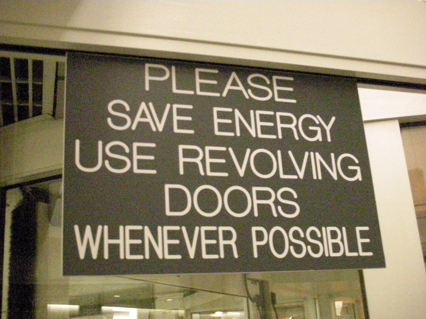A sign on a glass door reads, “Please save energy. Use revolving doors whenever possible.” A sign on a glass door reads, “Please save energy. Use revolving doors whenever possible.”