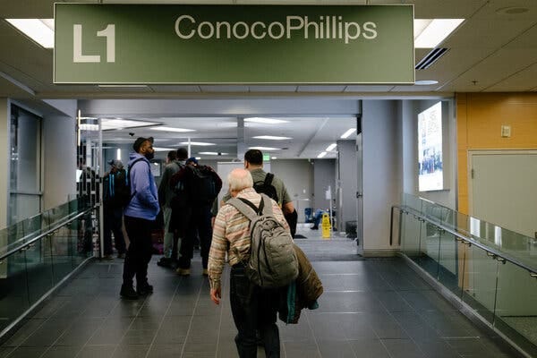 People on a ramp with backpacks walk toward a sign that says ConocoPhillips L1.