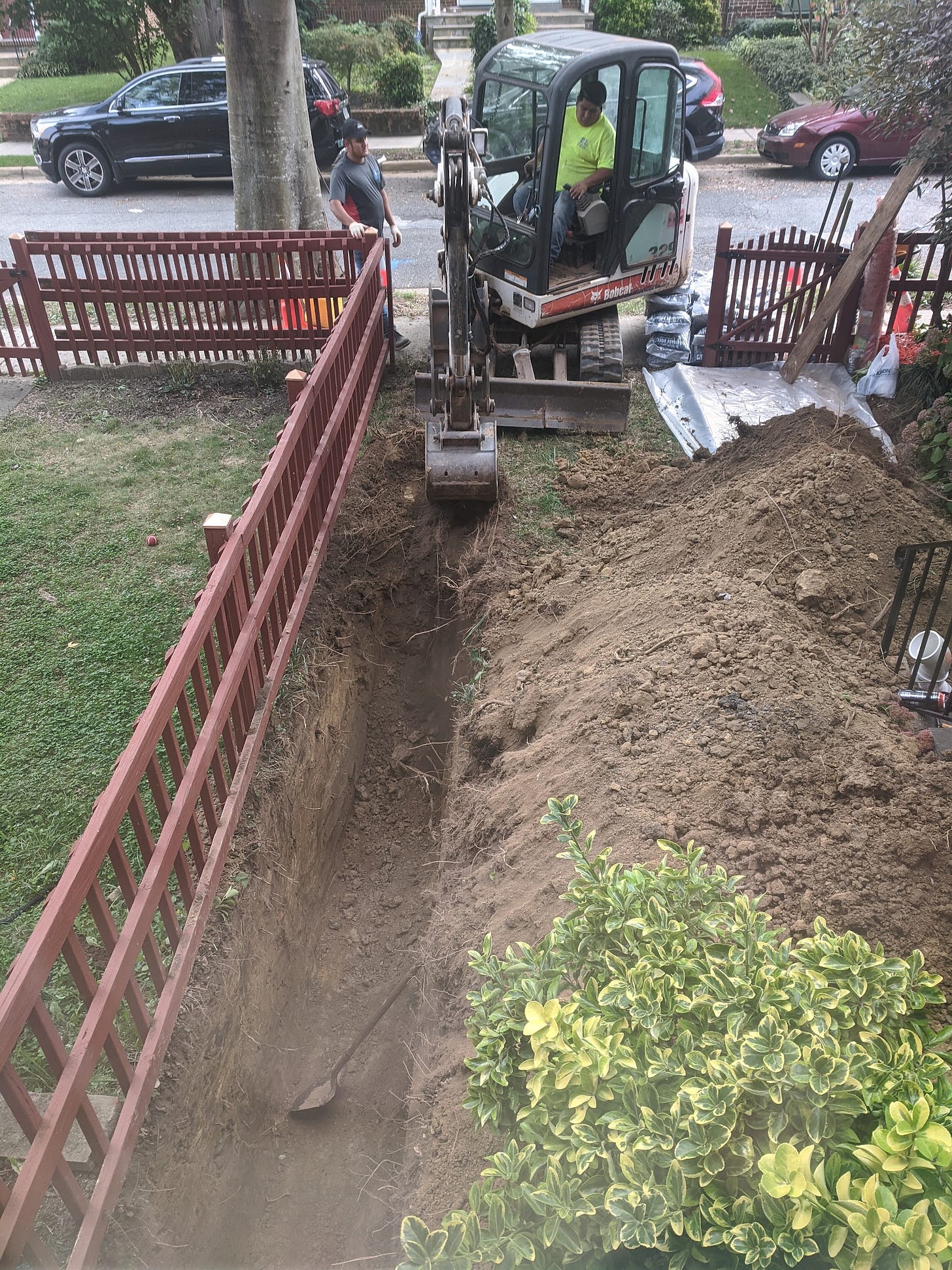 Workers dig a trench in my front yard, obliterating my lawn.
