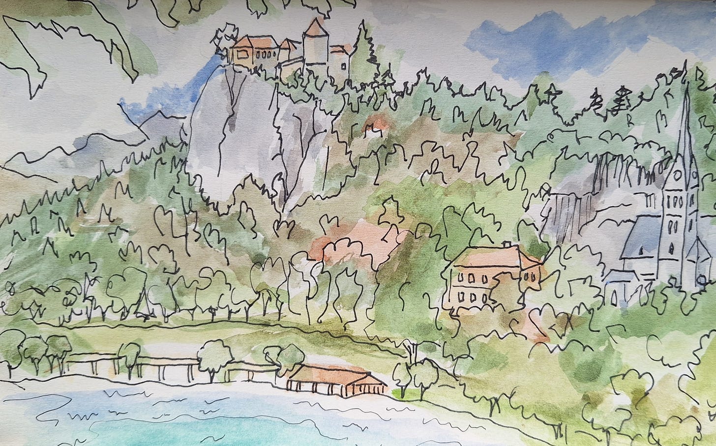 Pen and ink with watercolour sketch of the north shore of Lake Bled.  With boat houses,trees and a grassy bank in the foreground. A church, forested cliff and castle in the middle and mountains beyond.