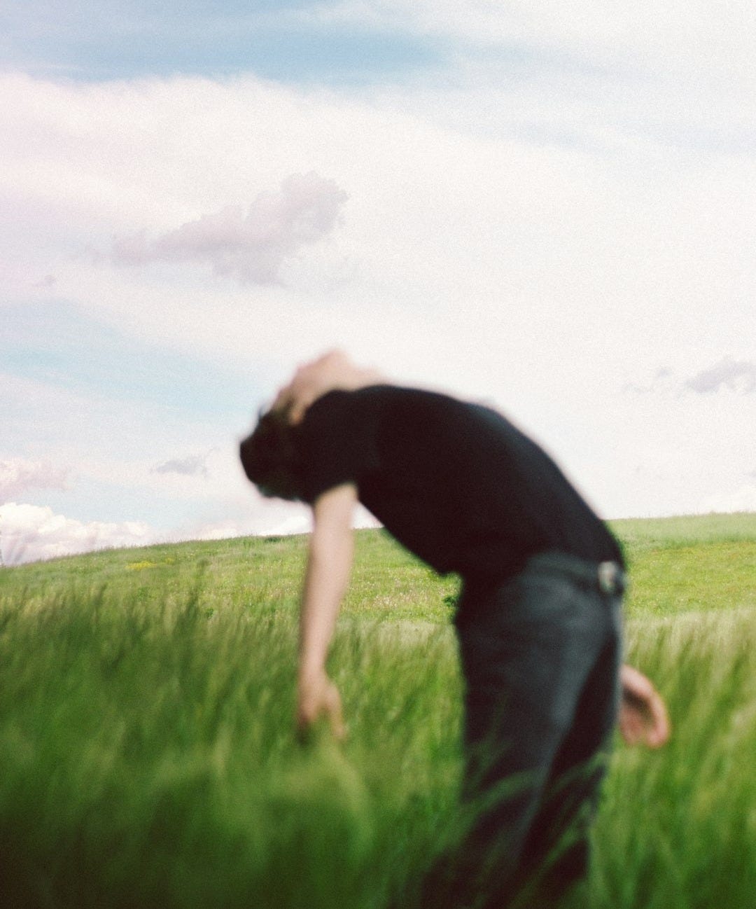 man in black t-shirt and gray denim jeans standing on green grass field during daytime man in black t-shirt and gray denim jeans standing on green grass field during daytime