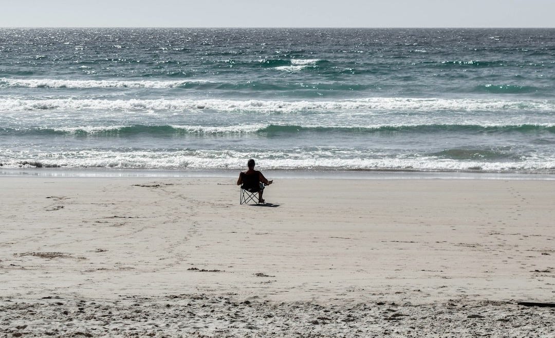 person in black wet suit carrying white surfboard walking on beach during daytime