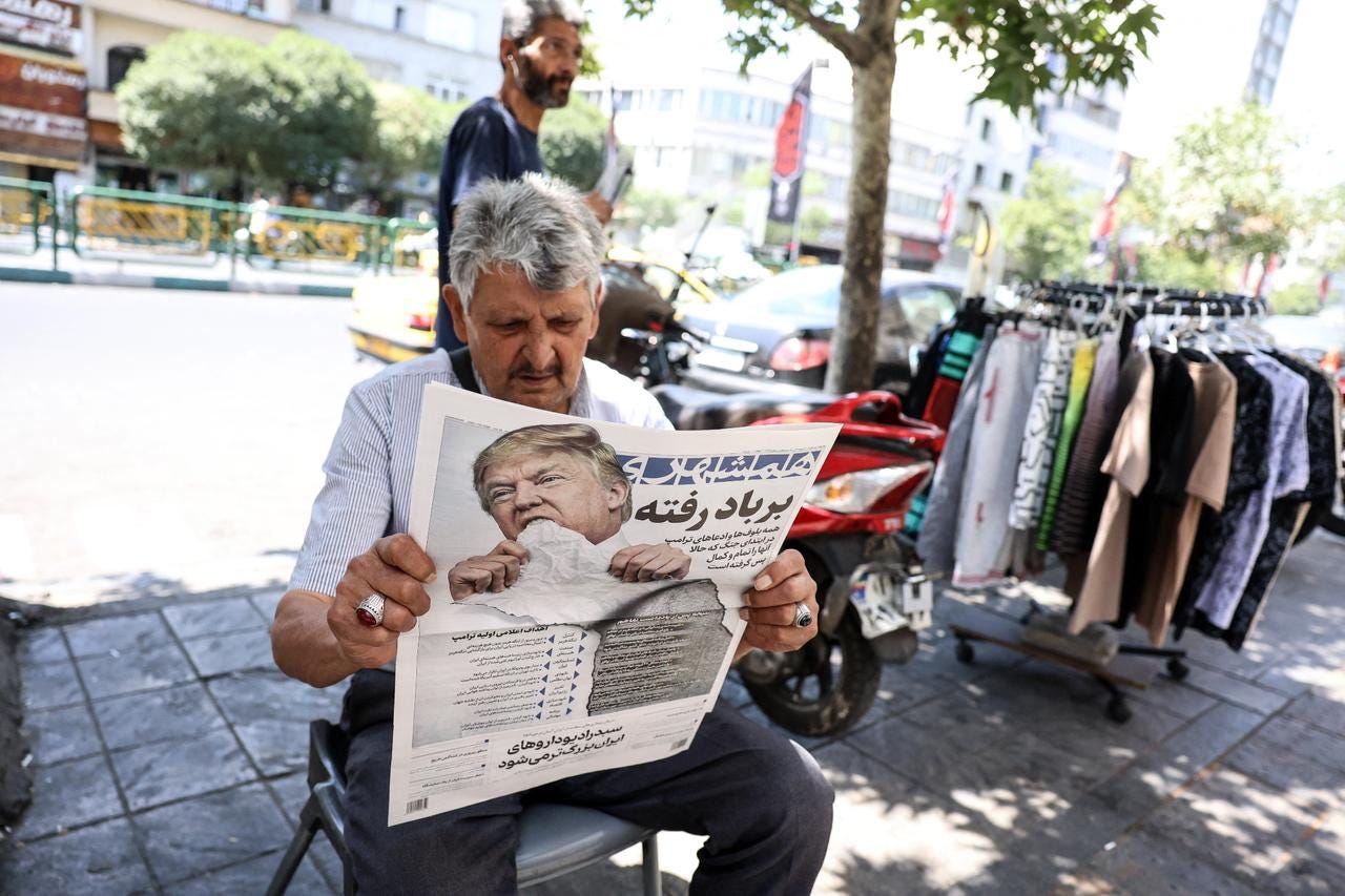 A man reads a copy of the Iranian daily newspaper Hamshahri bearing an image of the US president and a headline that reads 