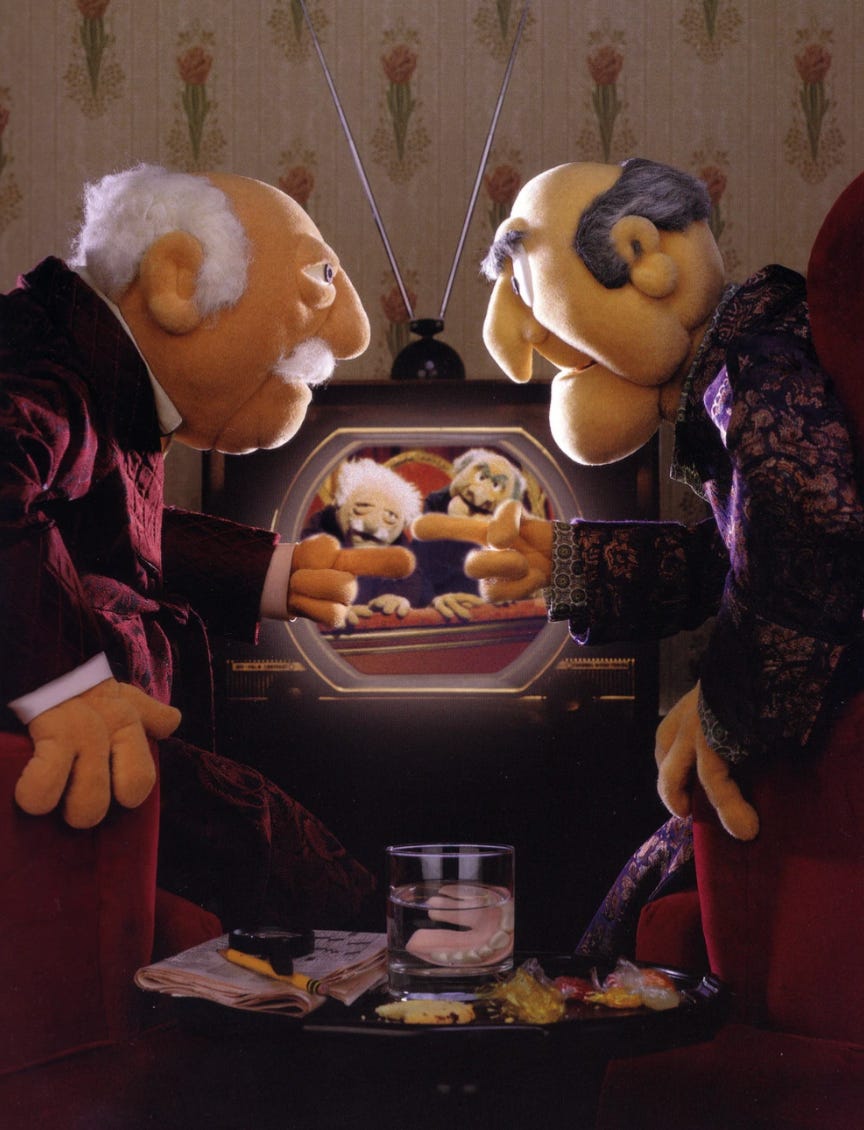 Waldorf and Statler point at each other while watching an image of themselves on a television Waldorf and Statler point at each other while watching an image of themselves on a television