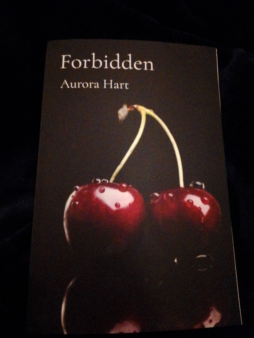 The poetry book by Aurora Hart called Forbidden showing cherries on a dark background The poetry book by Aurora Hart called Forbidden showing cherries on a dark background