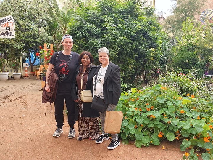 Three people are standing arm in arm, two are white, one is Black. They are smiling. There are plants in the background. They stand on dirt soil. The next foto shows a window with political stickers and many small photographs of faces in black and white collaged together.