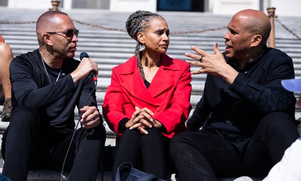 Hakeem Jeffries, Maya Wiley, and Cory Booker sit on the steps of the capitol talking to one another during their sit-in.