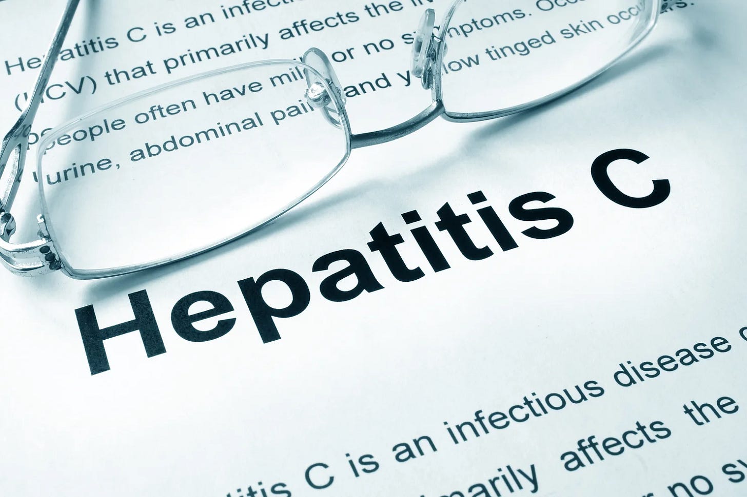 Glasses resting on a document titled "Hepatitis C" with detailed text below, suggesting medical content. White background, clinical tone.