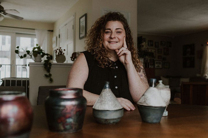 Various ceramic keepsake vessels (urns) of differing sizes and shapes, all raku fired atop a wooden table.