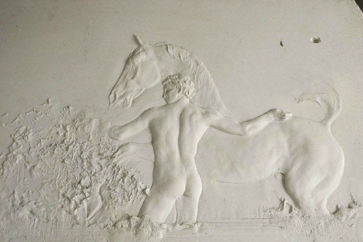 This may contain: a sculpture of a man and a dog on a white wall with paint chippings