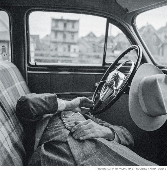 Photo of man in pinstripe suite asleep in car.