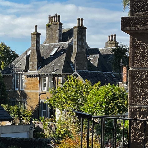 glimpse of a garden beyond a stone archway, the view beneath a low bridge, a grand stone house behind black iron railings