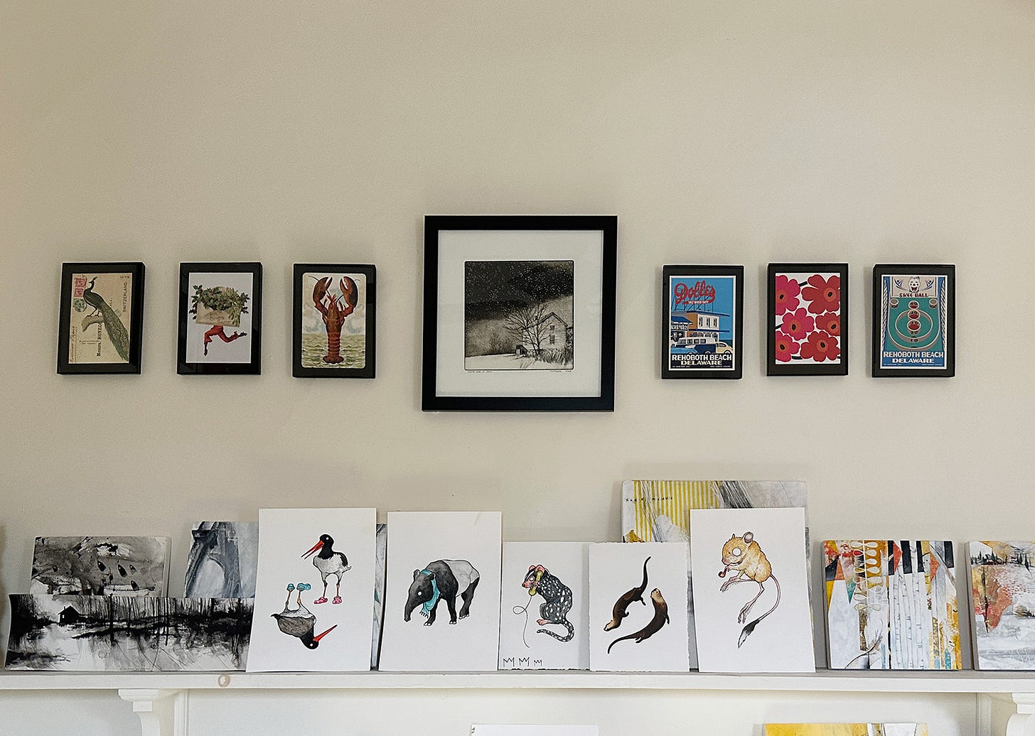 Some postcards from friends and travels, arrayed in small frames, flank one of my etchings above the shelves in my studio.