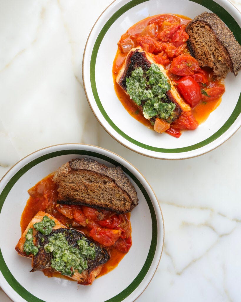Basil tomato salmon in a bowl with a slice of sourdough.