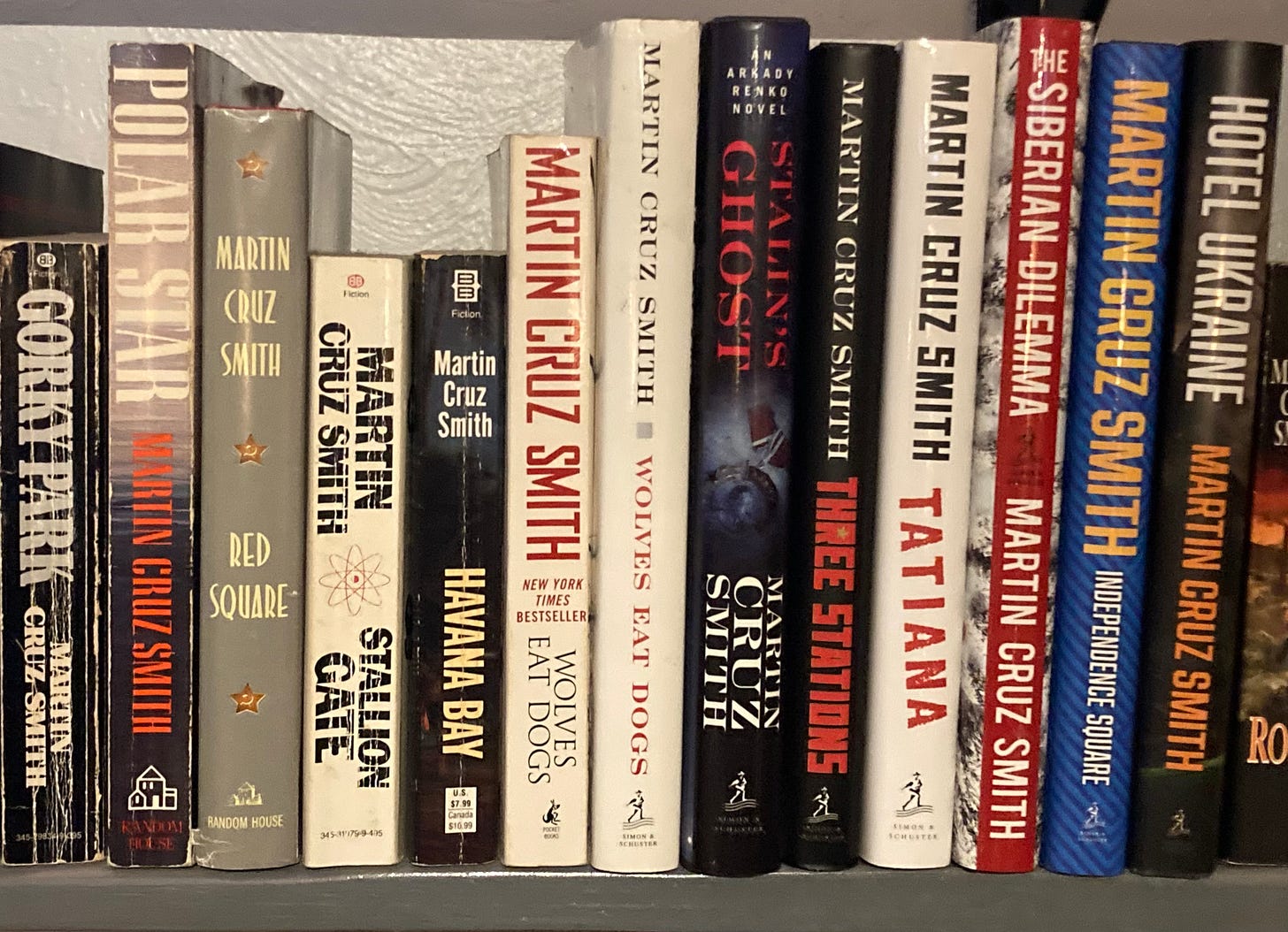 A bookshelf lined with Martin Cruz Smith novels, most from the Arkady Renko series, arranged in publication order from left to right. Visible spines include Gorky Park, Polar Star, Red Square, Havana Bay, Wolves Eat Dogs, Stalin’s Ghost, Three Stations, Tatiana, The Siberian Dilemma, Independence Square, and Hotel Ukraine. The worn earlier paperbacks contrast with newer hardcovers, showing decades of reading and collecting the full Renko saga.