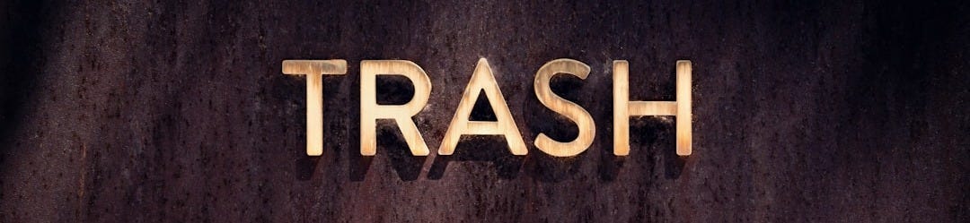 the word trash spelled with gold letters on a dark background