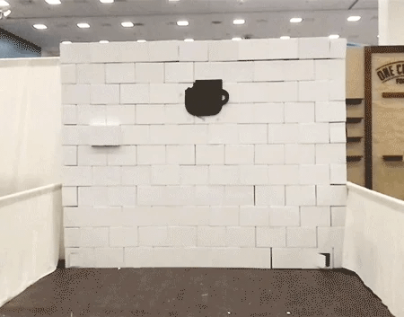 Two men burst through a wall made of cardboard boxes. Two men burst through a wall made of cardboard boxes.