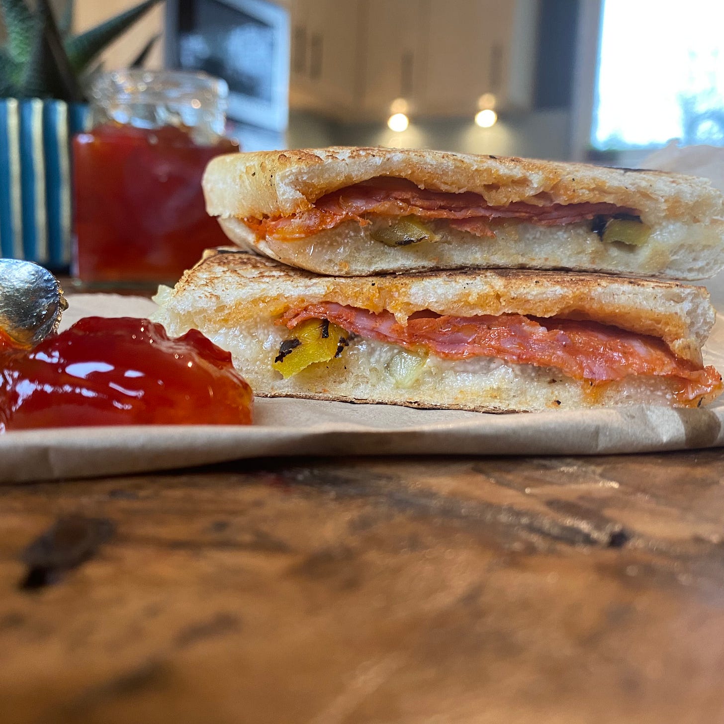 Cross section of a toasted sandwich made of chorizo, manchego cheese and yellow peppers, with a blob of jalapeno jam
