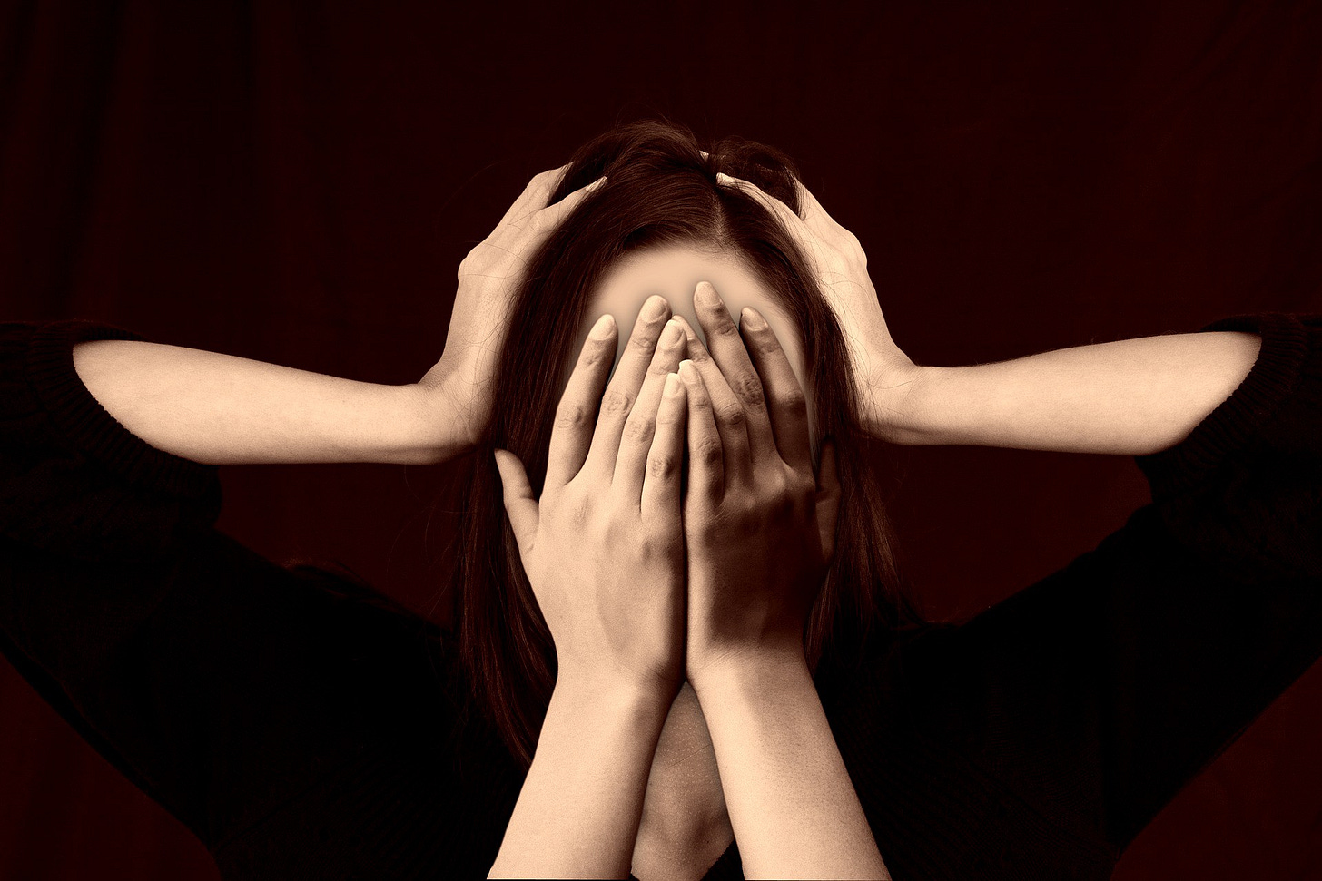 White woman gripping her head between her hands while other white hands cover her face White woman gripping her head between her hands while other white hands cover her face