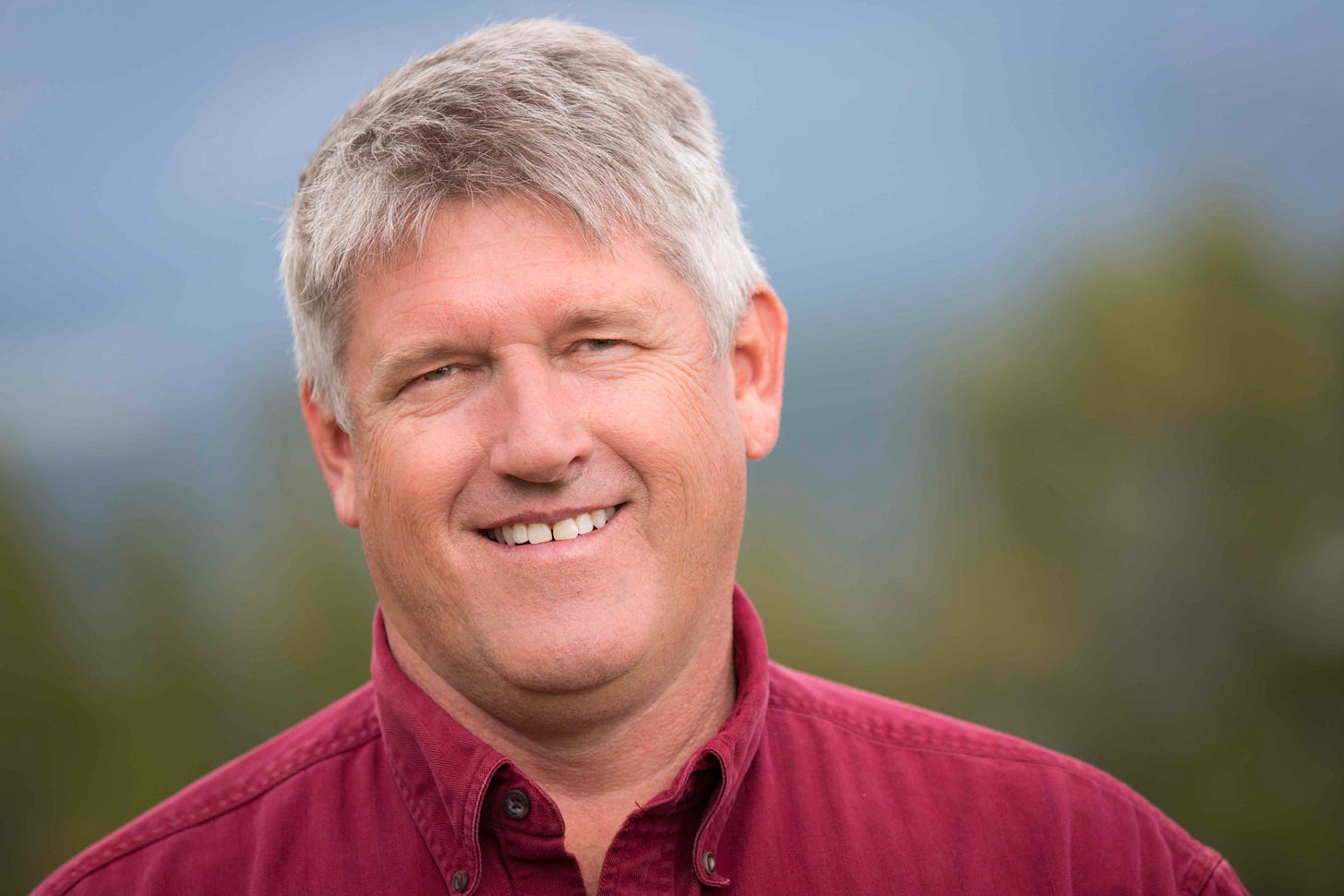 man with gray hair in red button down outside