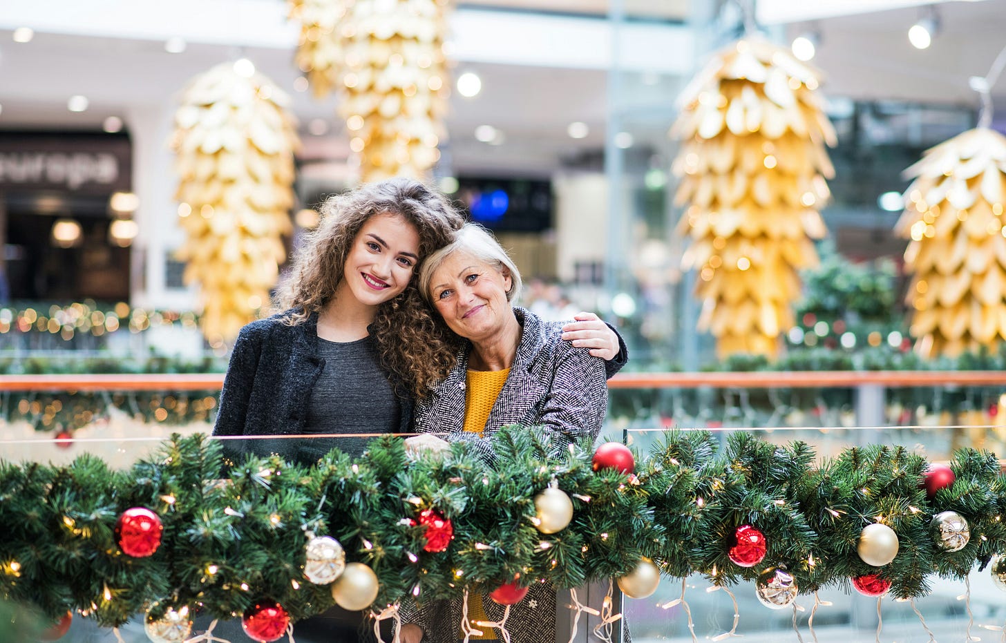 Two women stood together with Christmas decorations in the background Two women stood together with Christmas decorations in the background