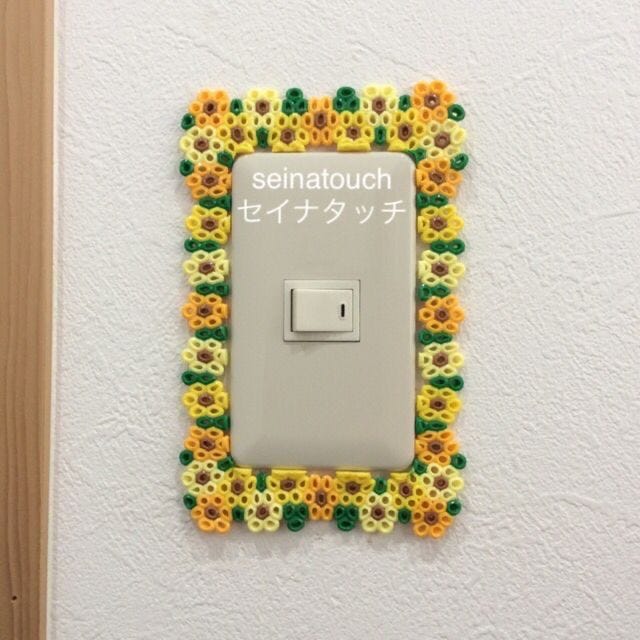 This may contain: a white light switch sitting on top of a wall next to a wooden frame with sunflowers This may contain: a white light switch sitting on top of a wall next to a wooden frame with sunflowers