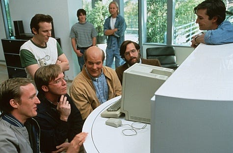 Founders gather around a vintage computer in the early days of Silicon Valley, showcasing how physical proximity shaped startup culture and innovation in the 1980s. Founders gather around a vintage computer in the early days of Silicon Valley, showcasing how physical proximity shaped startup culture and innovation in the 1980s.