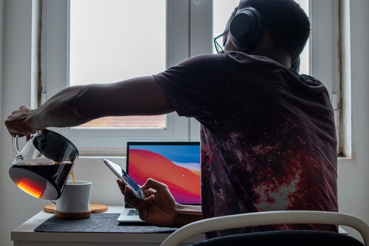 A man pouring coffee at his work desk