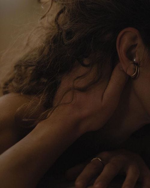 This may contain: a woman laying on top of a bed with her hand under her face and ear