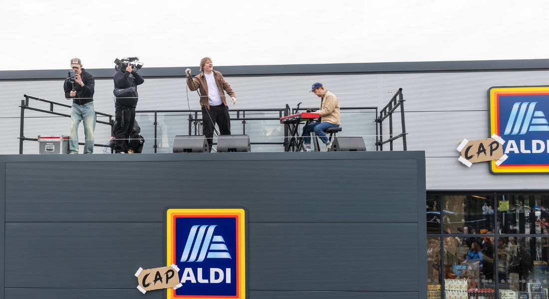 A man - Lewis Capaldi - on top of an Aldi with a band and film crew A man - Lewis Capaldi - on top of an Aldi with a band and film crew