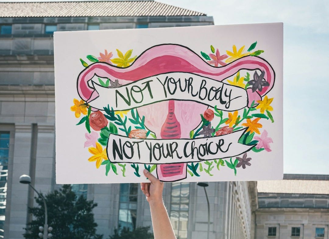a woman holding a sign that says not your baby, not your choice