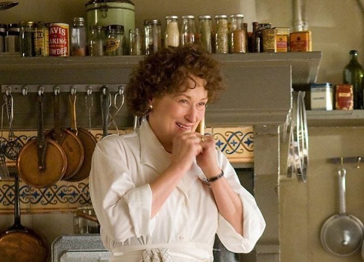 This may contain: a woman standing in front of a stove with pots and pans on the wall