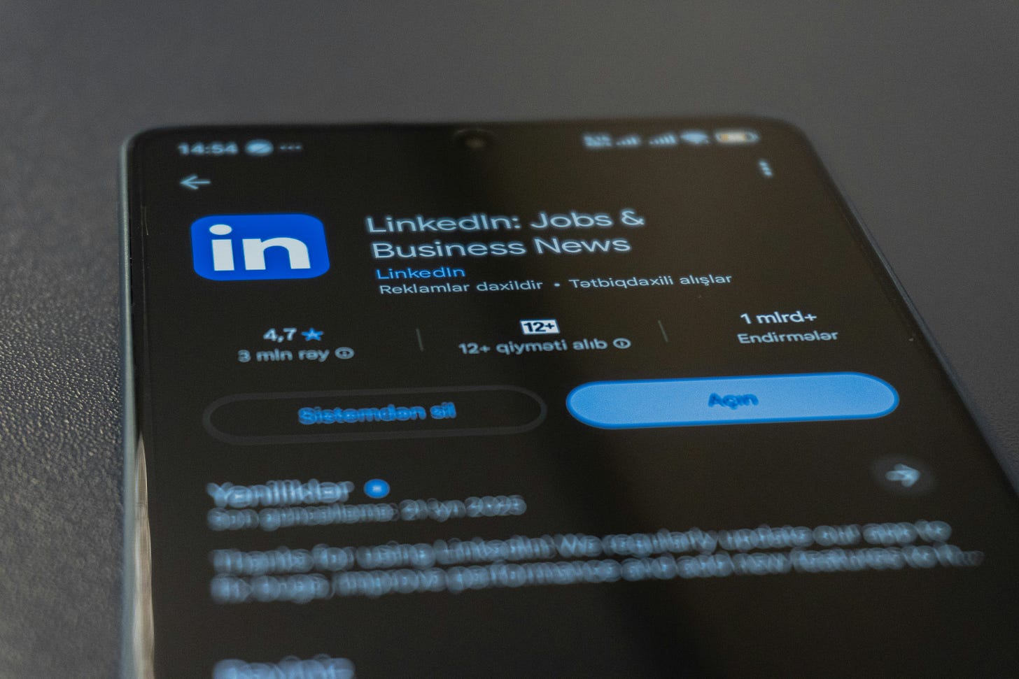 A picture of the top half of an iphone. It shows the app store screen to download the LinkedIn app. The LinkedIn logo on the top left is a blue square with the letters "in" in white lowercase. The name of the app is "LinkedIn: jobs and business news" on the right, in white letters.