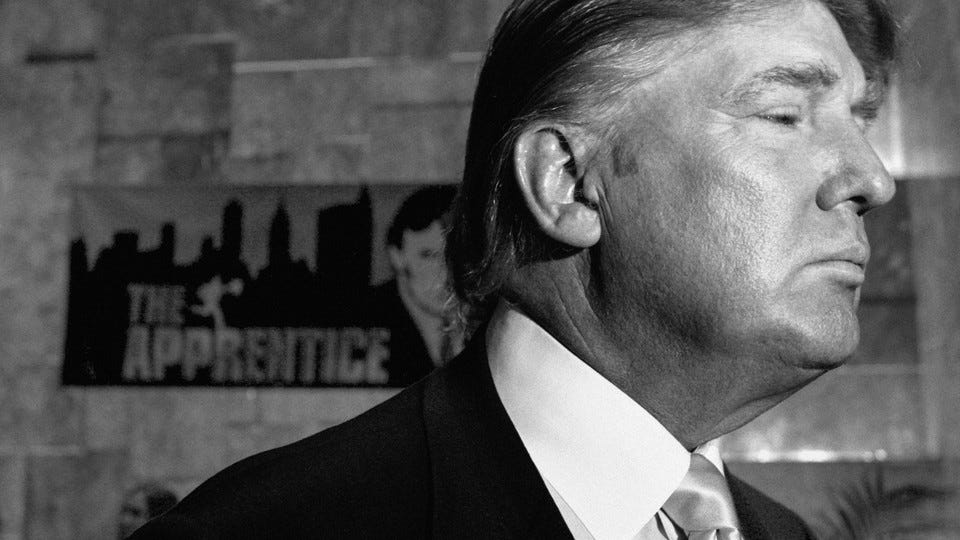 Donald Trump in front of a sign for "The Apprentice"