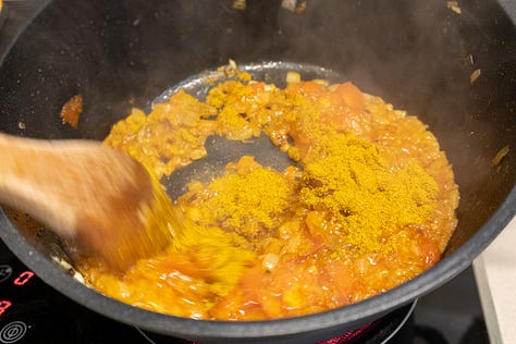 Olla con cebolla dorándose, añadiendo tomate y especias y luego el pollo