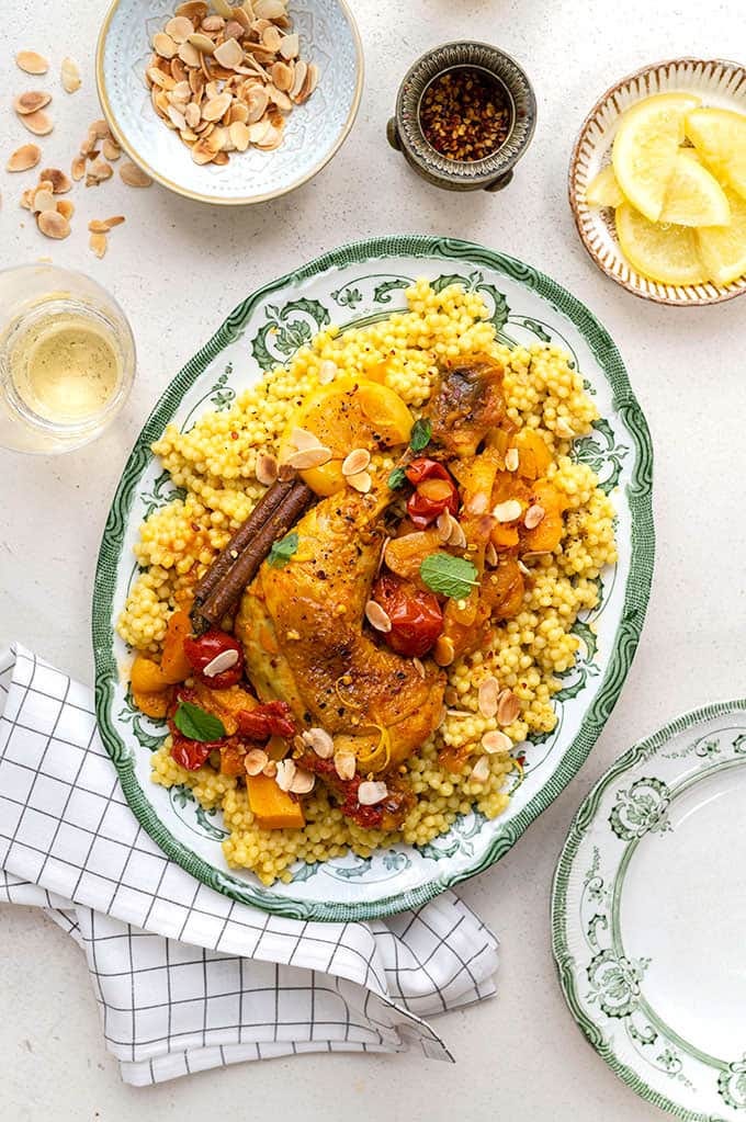 Overhead shot of platter of Moroccan chicken tagine served over giant couscous Overhead shot of platter of Moroccan chicken tagine served over giant couscous