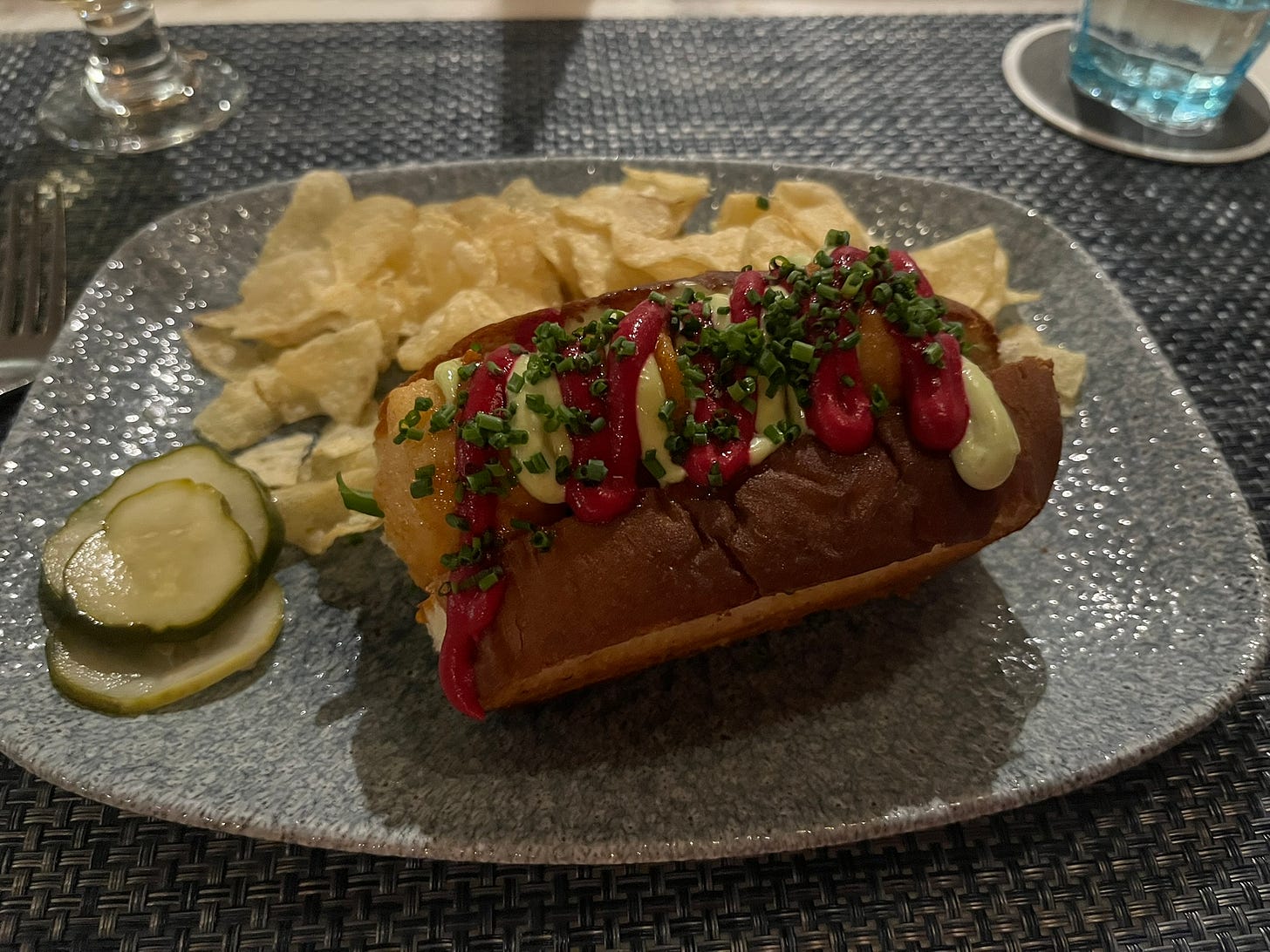 A po’ boy sandwich with browned scallops, purple beet sauce, mayonnaise and chives, served with fries and pickles