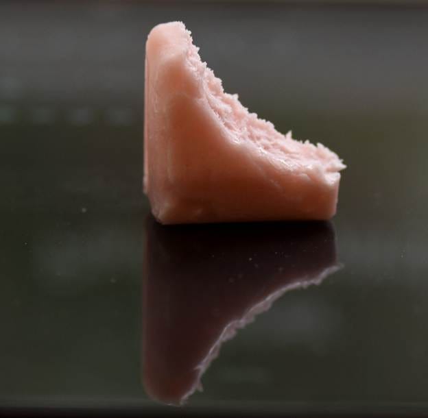 A piece of pink food on a black surface

AI-generated content may be incorrect.