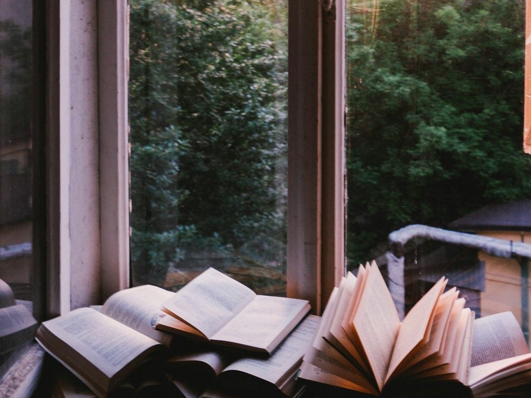 books beside window during sunset