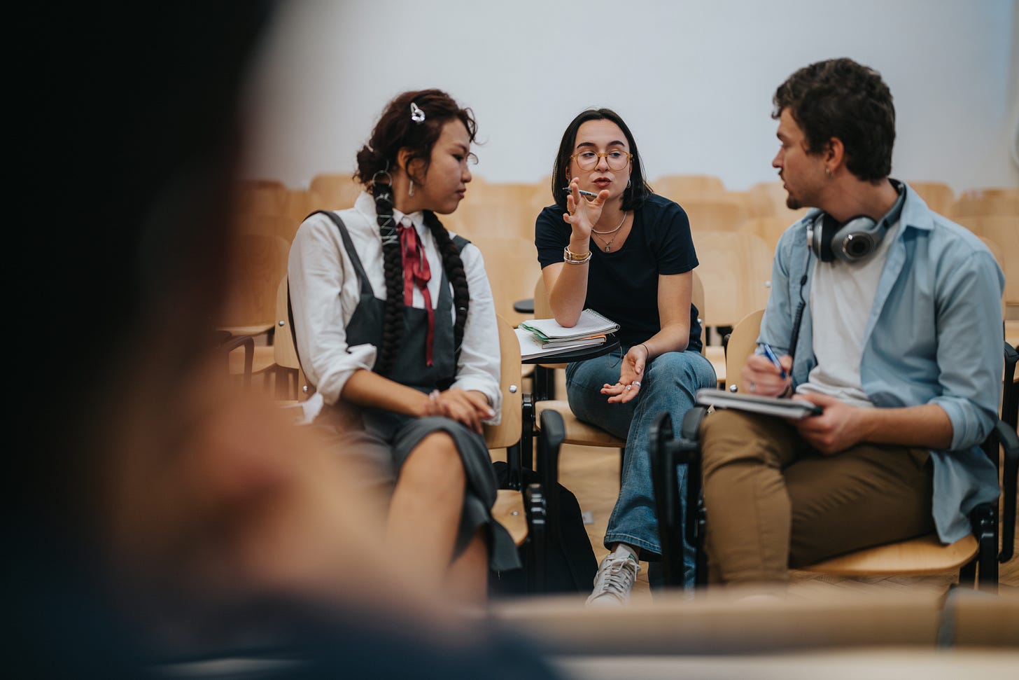 Three students engaging in a discussion in a classroom