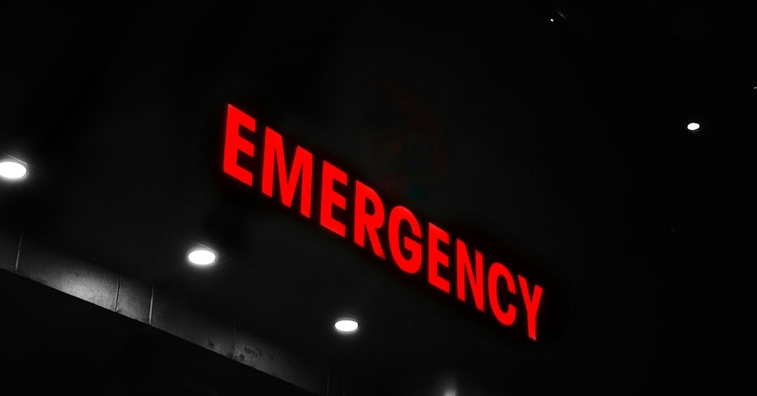 Red emergency sign illuminates a dark building entrance. Red emergency sign illuminates a dark building entrance.