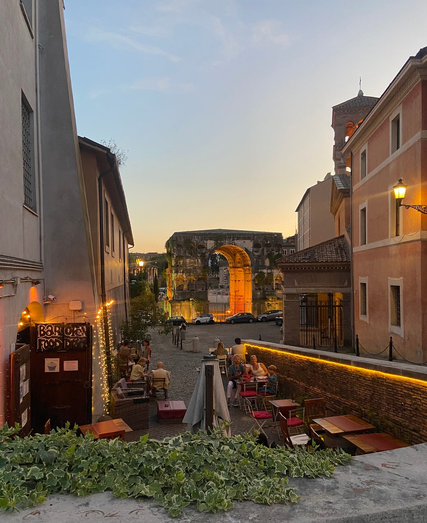 Evening aperitivo with the Arco di Giano (Arcus Quadrifons) in the background. Rome, Italy.