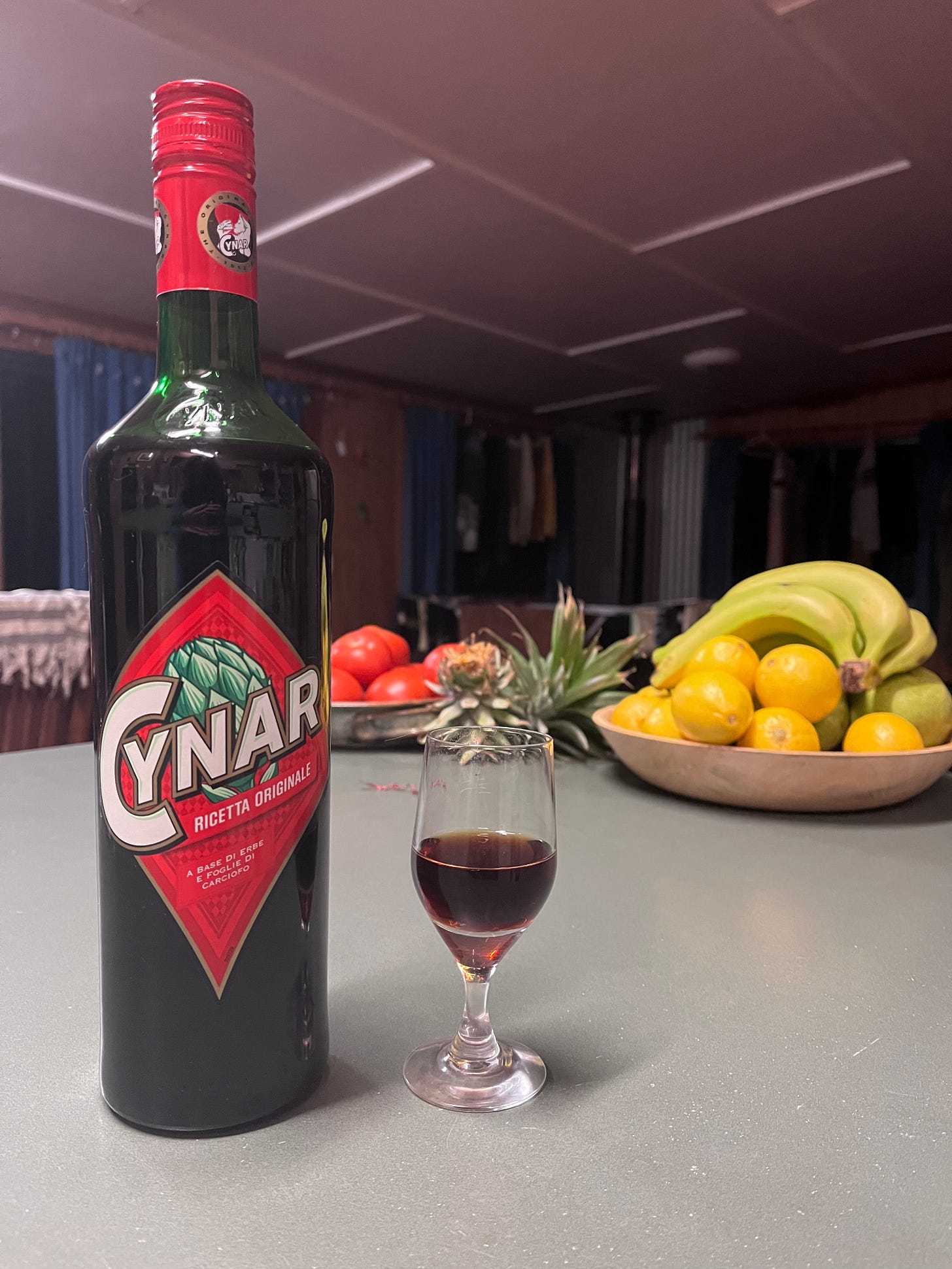 A bottle of Cynar sits on the kitchen countertop with a glass poured.