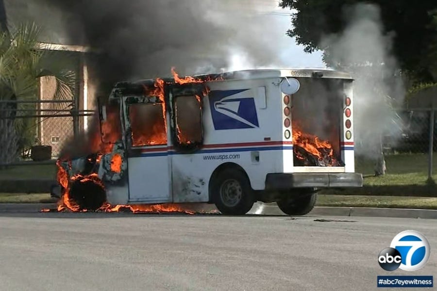 Video screenshot of a postal truck engulfed in flames. The rear door is fully open, so the truck's burning, charred contents can be seen in the cargo compartment. It's all so thoroughly destroyed that nothing recognizable as mail or parcels can be seen. Video screenshot of a postal truck engulfed in flames. The rear door is fully open, so the truck's burning, charred contents can be seen in the cargo compartment. It's all so thoroughly destroyed that nothing recognizable as mail or parcels can be seen.