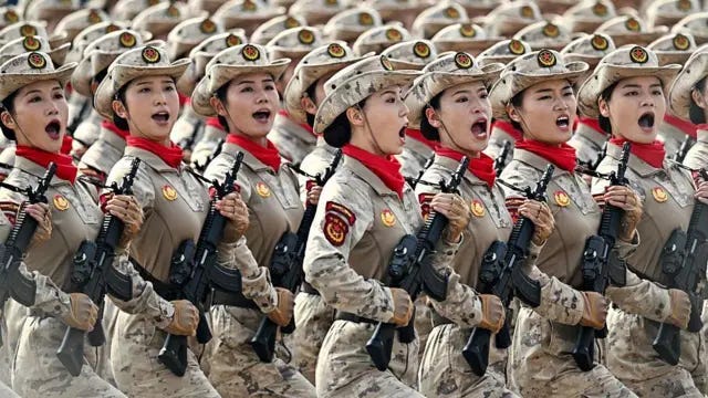 Mujeres soldados con uniforme militar y sombreros marchan con rifles