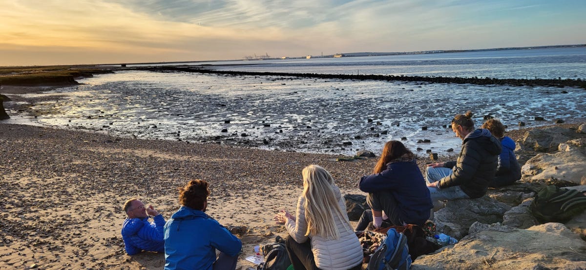 a group of people resting where the Thames flows into the sea