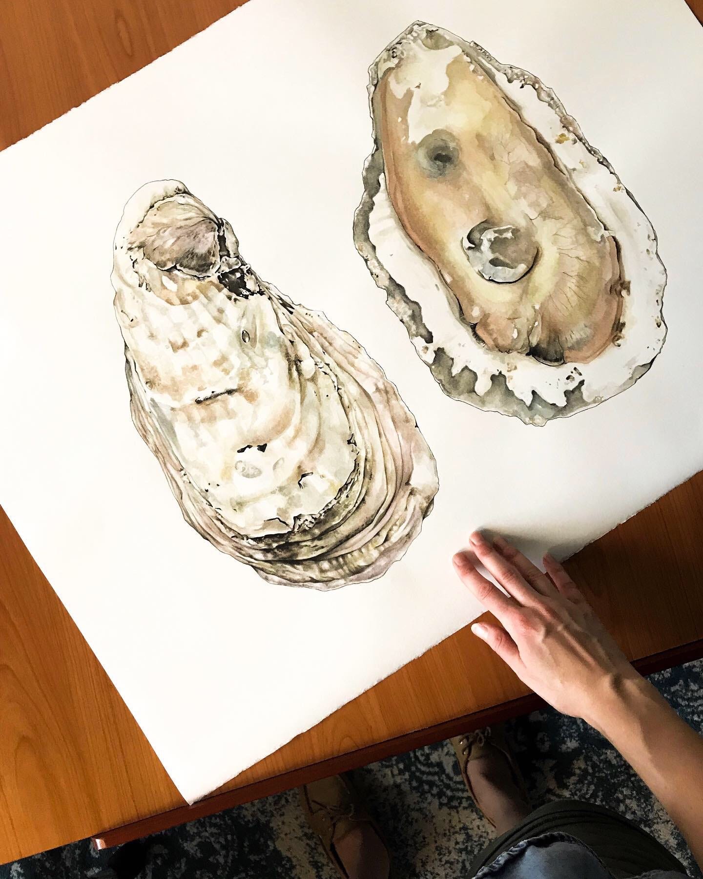 A birds eye view of the painting on my studio desk, with my hand reaching in in the bottom right corner, touching the paper. 